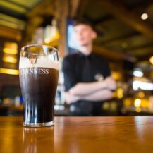 A pint of Guinness on a wooden bar counter in a cosy pub atmosphere at Scotts Hotel Killarney.