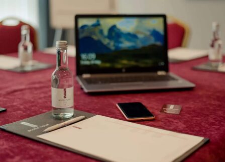 Elegant conference setup at Scotts Hotel Killarney with laptop, notepad, phone, and bottled water.