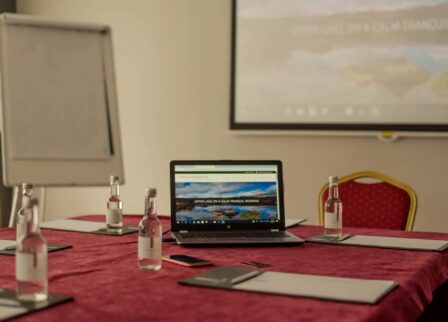 Conference room at Scotts Hotel Killarney with laptop, water bottles, and notepads on a red table.