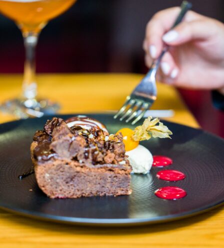 Person enjoying a rich chocolate dessert at Scotts Hotel Killarney, with a cocktail on the table.