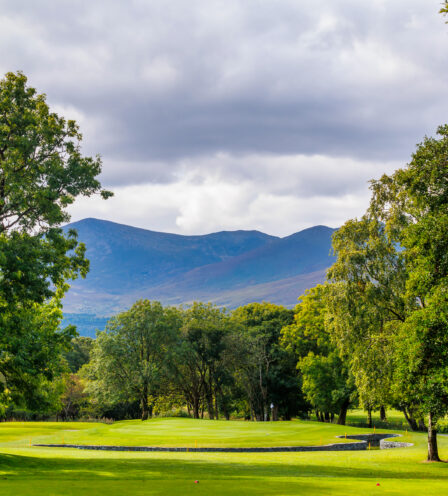 Lush green golf course at Scotts Hotel Killarney with mountain views under cloudy skies.