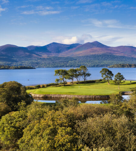 Scenic view of lush greenery and mountains by a tranquil lake near Scotts Hotel Killarney.