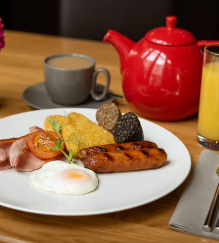 Full Irish breakfast with tea and orange juice at Scotts Hotel Killarney, adorned with pink flowers.