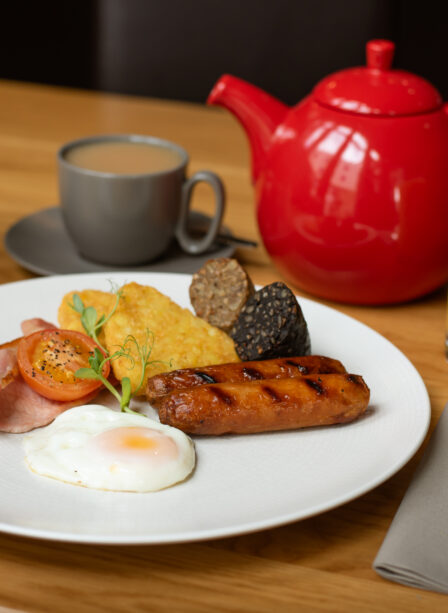 Full Irish breakfast with tea and orange juice at Scotts Hotel Killarney, adorned with pink flowers.