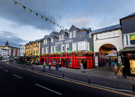 People walking by the welcoming entrance of Scotts Hotel Killarney, under a twilight sky.