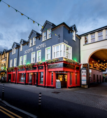 Evening view of Scotts Hotel in Killarney with vibrant red facade and inviting entrance.