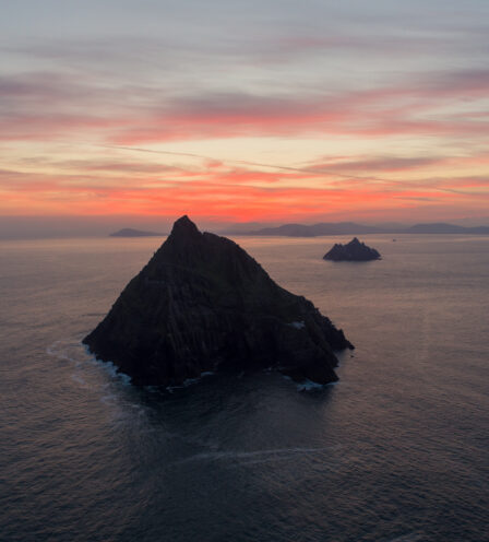 Scenic sunset over rocky islands in calm sea, creating a serene and picturesque atmosphere.