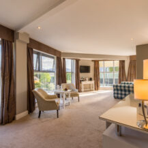 Spacious hotel room at Scotts Hotel Killarney with large windows, cosy seating, and soft lighting.