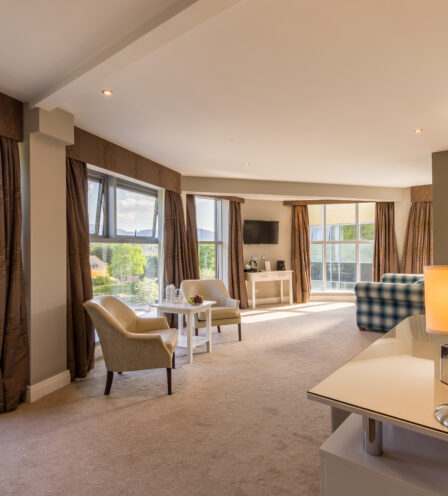 Spacious hotel room at Scotts Hotel Killarney with large windows, cosy seating, and soft lighting.