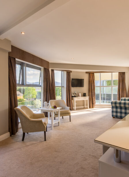 Spacious hotel room at Scotts Hotel Killarney with large windows, cosy seating, and soft lighting.