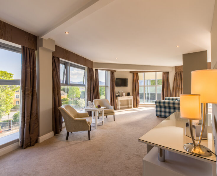 Spacious hotel room at Scotts Hotel Killarney with large windows, cosy seating, and soft lighting.