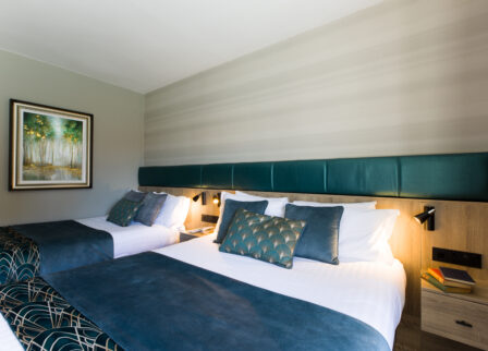 Elegant hotel room with two neatly made beds, soft lighting, and a nature painting on the wall.