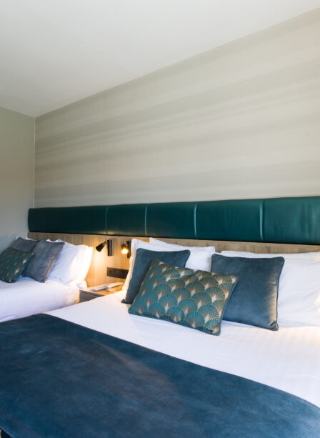 Elegant hotel room with two neatly made beds, soft lighting, and a nature painting on the wall.