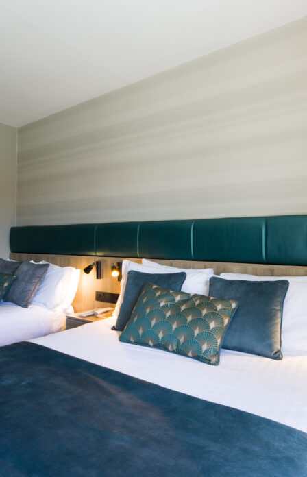 Elegant hotel room with two neatly made beds, soft lighting, and a nature painting on the wall.
