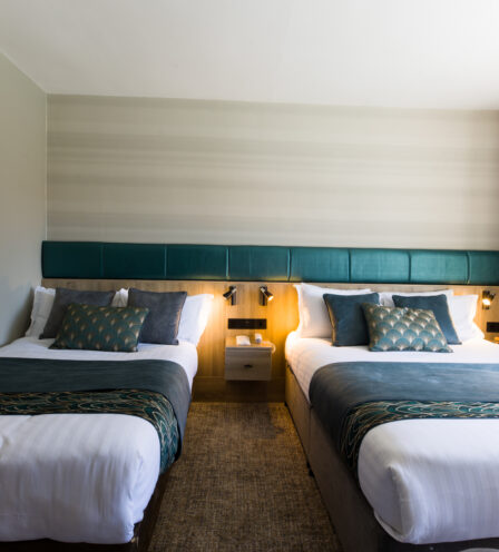 Elegant twin beds in a cosy hotel room at Scotts Hotel Killarney, featuring modern decor.