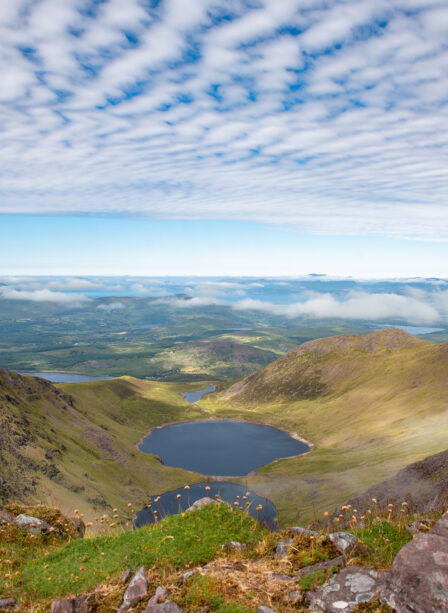 Stunning view of a serene lake surrounded by lush mountains under a sky with scattered clouds.