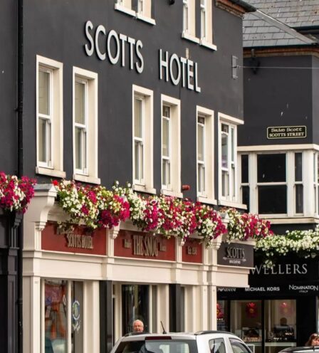 Visitors stroll past Scotts Hotel Killarney, adorned with colourful floral displays.
