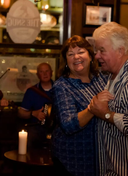 A joyful couple dances to live music in a warm, cosy atmosphere at Scotts Hotel Killarney.