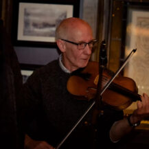 A musician plays the violin in a warm, cosy setting at Scotts Hotel Killarney.