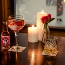 Cosy bar setting at Scotts Hotel with cocktails, candles, and roses, creating a warm atmosphere.