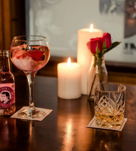 Cosy bar setting at Scotts Hotel with cocktails, candles, and roses, creating a warm atmosphere.