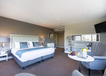 Spacious, elegant hotel room with comfy king-size bed, seating area, and fresh fruit at Scotts Hotel Killarney.
