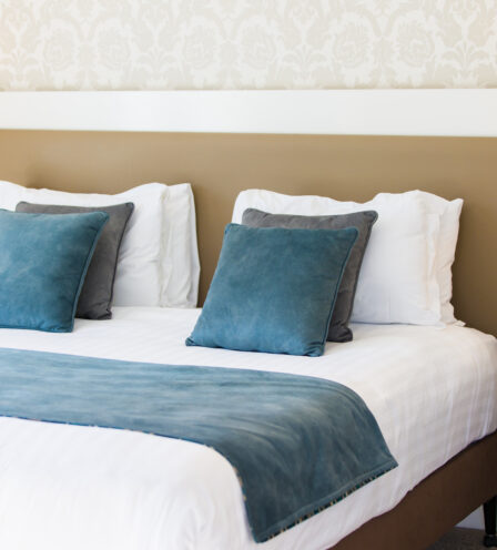 Elegant double bed with blue cushions in a cosy hotel room at Scotts Hotel Killarney.