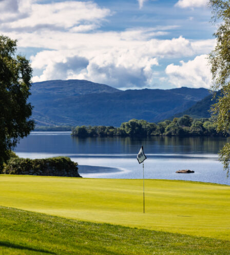 Scenic view of a golf course by a tranquil lake with mountains in the background at Scotts Hotel Killarney.