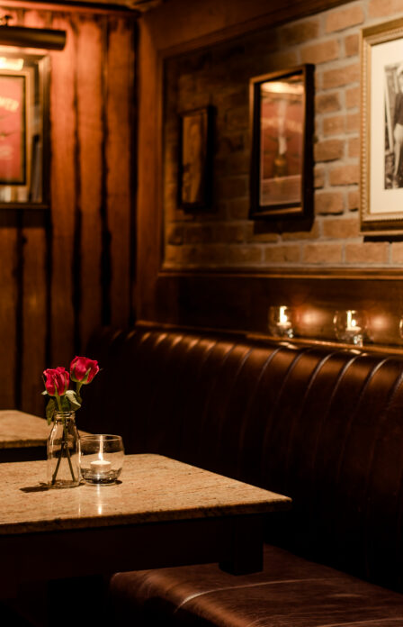 Cosy dining area with red roses at Scotts Hotel Killarney, warm lighting and framed art on walls.