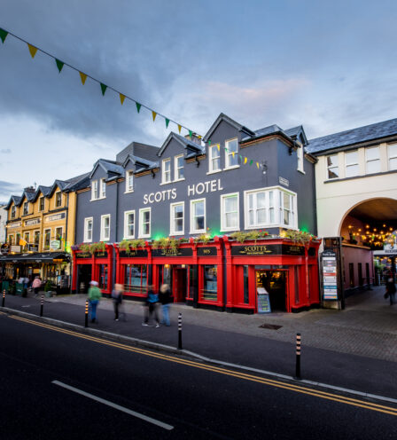 Evening street view of Scotts Hotel Killarney with lively pedestrians and illuminated shopfronts.
