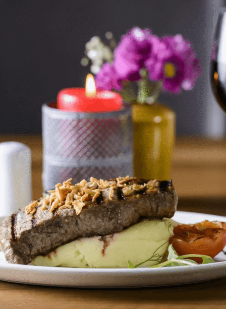 Elegant steak dinner with wine at Scotts Hotel Killarney, featuring flowers and a candle.