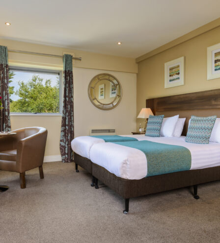 Modern hotel room with a cosy bed, elegant decor, and seating area at Scotts Hotel Killarney.