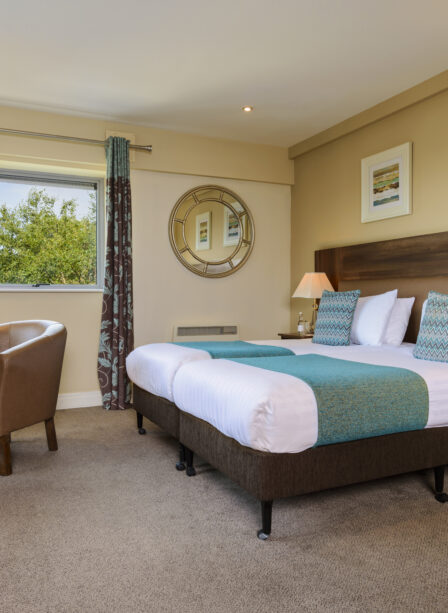 Modern hotel room with a cosy bed, elegant decor, and seating area at Scotts Hotel Killarney.