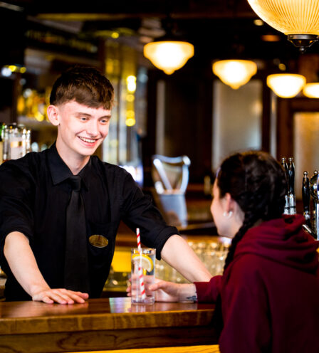 Friendly bartender serving drinks to a guest at Scotts Hotel Killarney bar.
