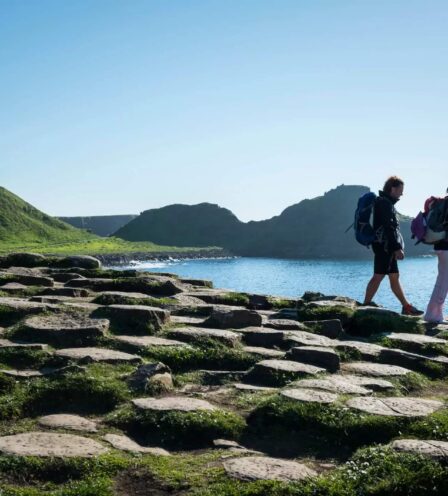 Scenic coastal walk with hikers at Giant's Causeway, under a clear blue sky.