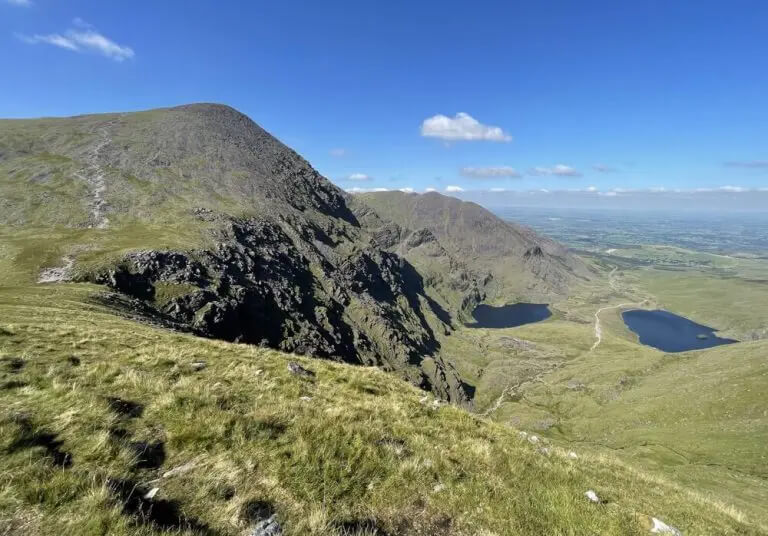 Stunning view of lush green mountains and serene lakes near Scotts Hotel Killarney, with clear blue skies.