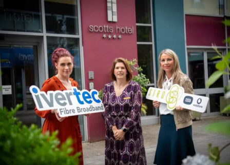 Women holding signs stand outside Scotts Hotel Killarney, highlighting local partnerships.