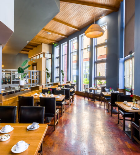 Elegant dining area with wooden tables, leather chairs, and large windows at Scotts Hotel Killarney.