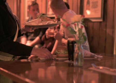 Busy bar scene at Scotts Hotel Killarney with guests enjoying drinks and a server delivering food.