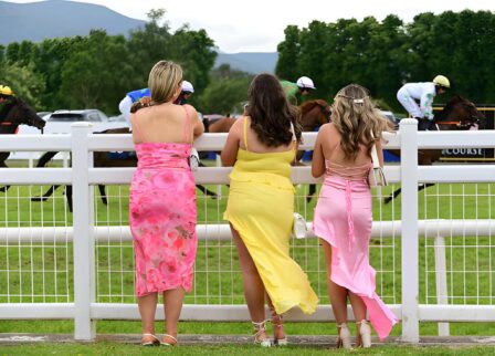 Three women in colourful dresses enjoy a lively horse race at Killarney venue.