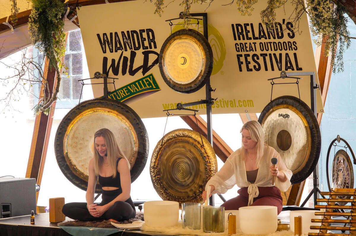 Two women performing a soothing sound healing session at an outdoor festival.