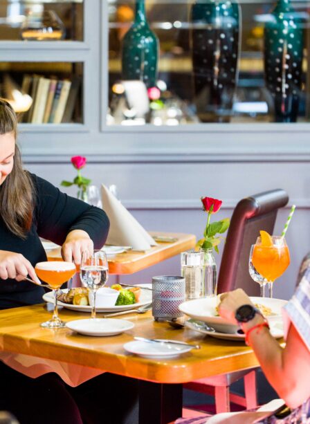 Two women enjoy dining at Scotts Hotel Killarney, with cocktails and elegant decor around them.