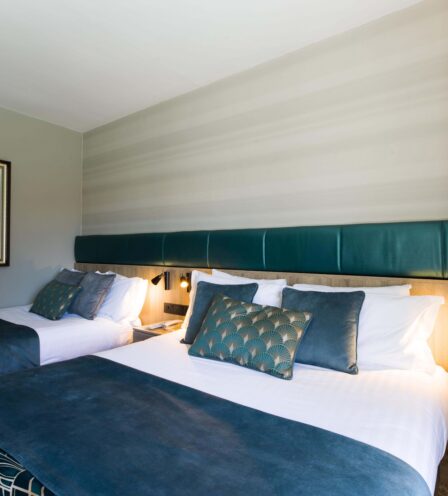 Cosy double beds in a warmly lit hotel room with elegant decor.