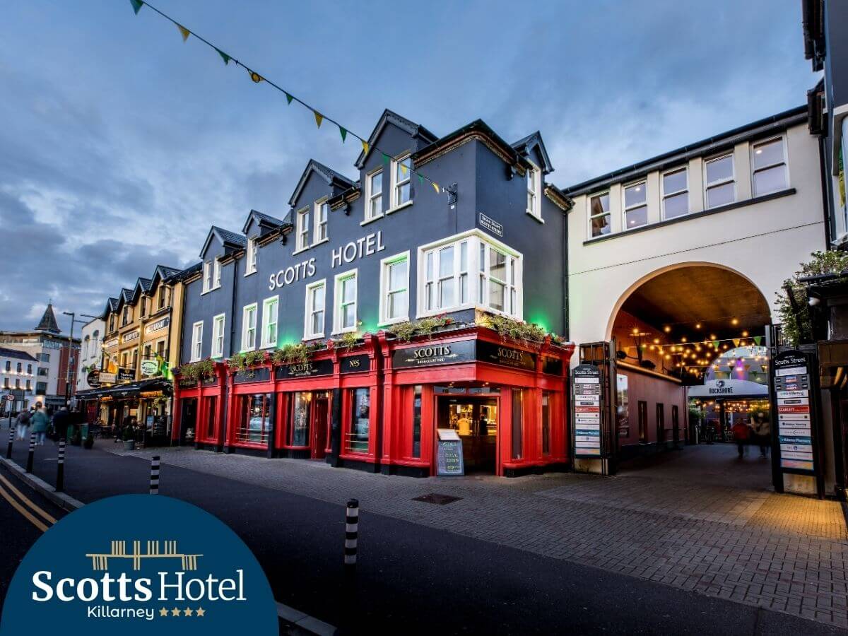 Exterior of Scotts Hotel Killarney at dusk, with inviting lighting and a lively street view.