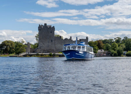 Scenic boat tour near historic castle on a sunny day at Killarney's Scotts Hotel.
