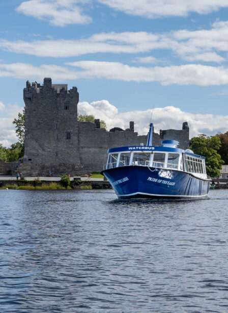 Scenic boat tour near historic castle on a sunny day at Killarney's Scotts Hotel.