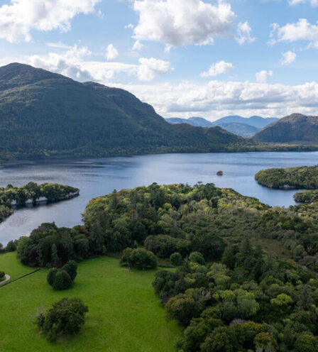 Aerial view of lush green landscapes and tranquil lake near Killarney.