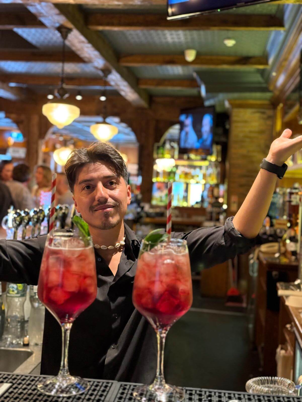 Bartender at Scotts Hotel serves vibrant cocktails in a warm, inviting bar setting.