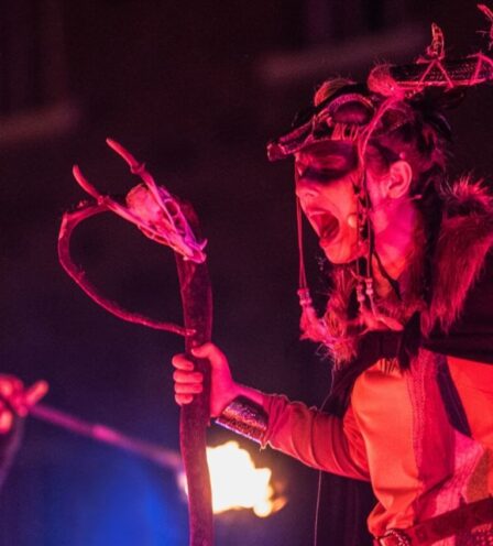 Roaring costumed performer with antler headpiece and staff, night-time fire show outside Scotts Hotel Killarney