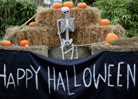Halloween display at Scotts Hotel Killarney with a skeleton on hay bales, pumpkins and a "HAPPY HALLOWEEN!" banner